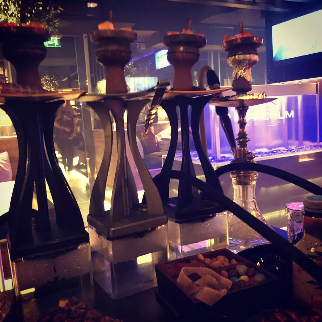 Mehrere moderne Shishas auf einem Tisch in der Shisha Bar Hamburg Eimsbüttel, umgeben von Snacks und stilvoller Beleuchtung.