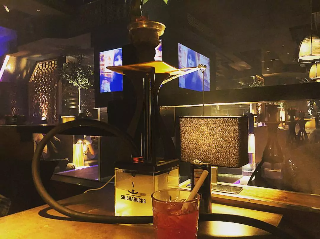 Eine Shisha und ein Getränk in einem stilvoll beleuchteten Shisha Café in Hamburg Hammerbrook, mit gemütlicher Atmosphäre und moderner Einrichtung.