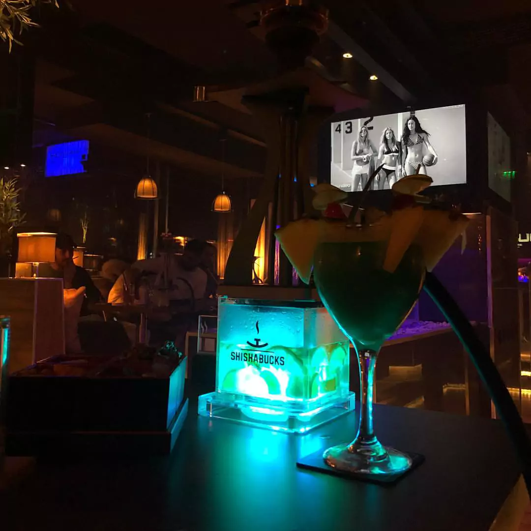 Eine Shisha und ein tropischer Cocktail in der Shisha Bar Hammerbrook bei stimmungsvoller Beleuchtung und moderner Einrichtung.