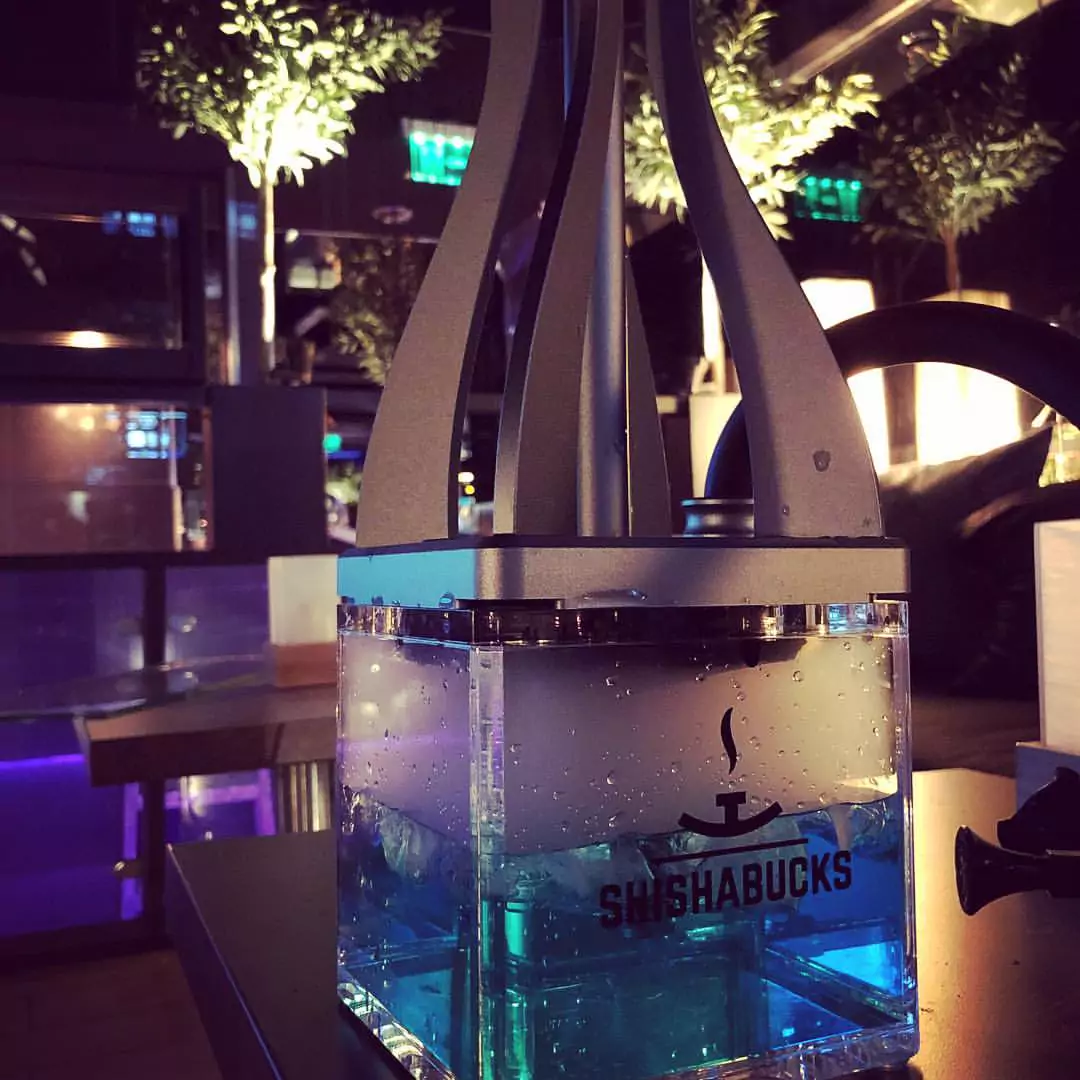 Moderne Shisha mit blauem Wasser in einem transparenten Glasbehälter in einer stilvollen Shisha-Bar.