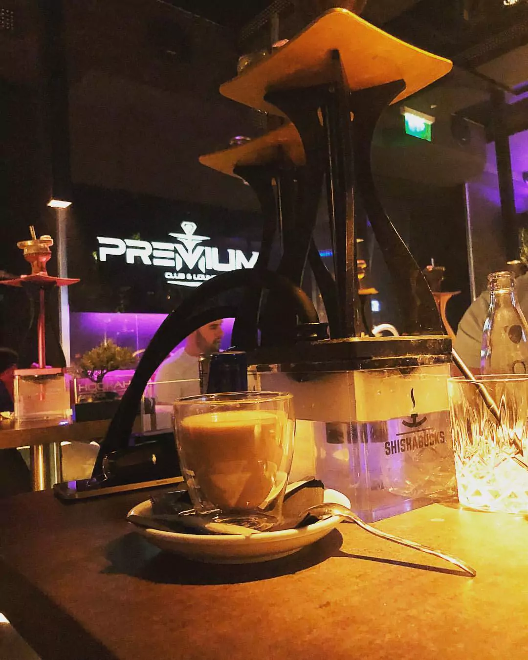 Ein Kaffee und eine moderne Shisha in einer stilvollen Shisha-Bar mit dezenter Beleuchtung.