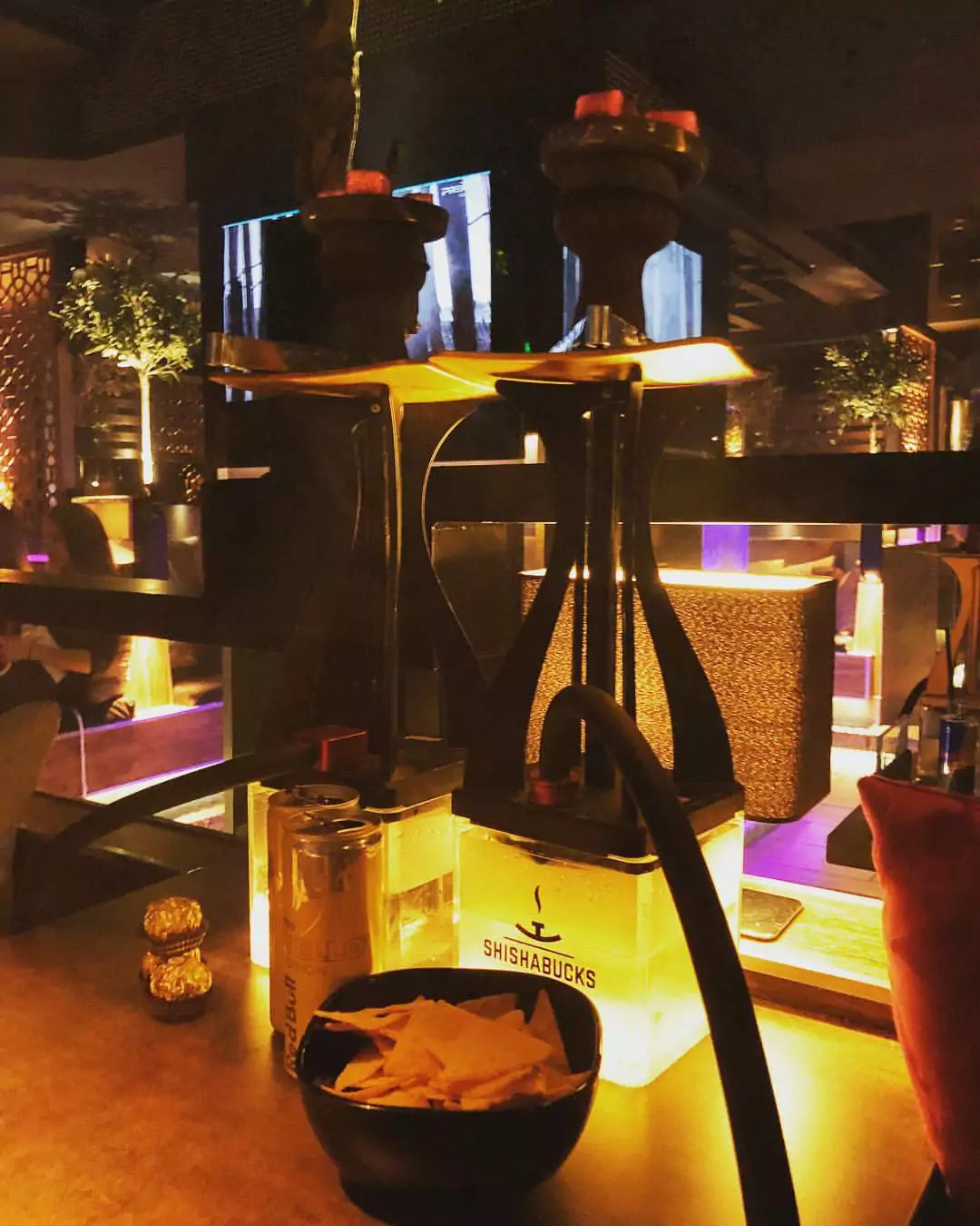 Zwei moderne Shishas und Snacks auf einem Tisch in der stilvoll beleuchteten Shishabar Berliner Tor mit gemütlicher Atmosphäre.