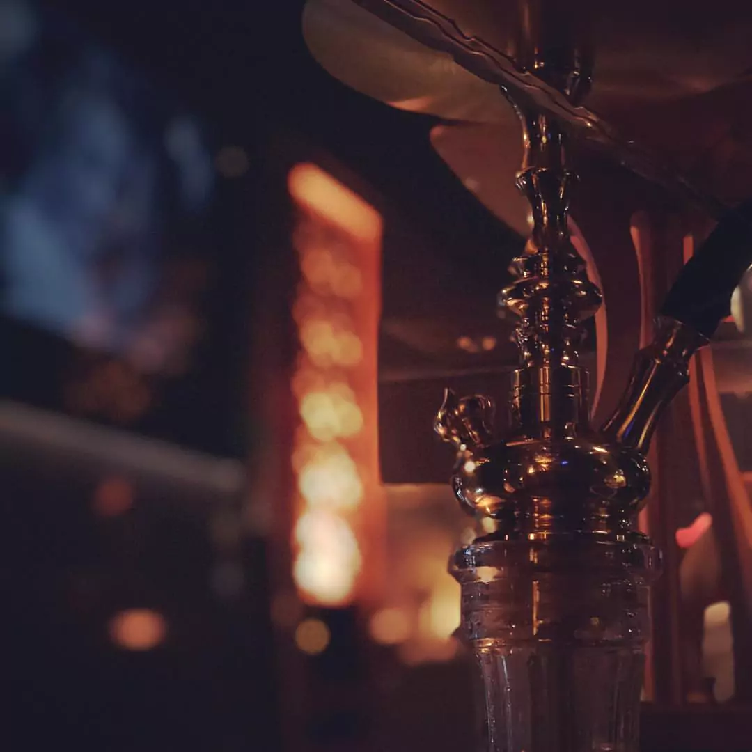 Detailaufnahme einer glänzenden Shisha in einer stimmungsvoll beleuchteten Shisha-Bar.