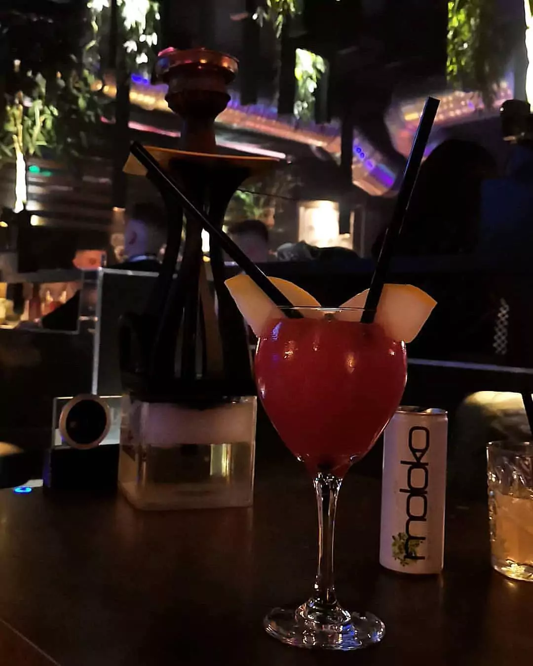 Shisha und Cocktail in einem stilvollen Shisha-Bar-Ambiente, mit sanfter Beleuchtung und üppiger Dekoration.