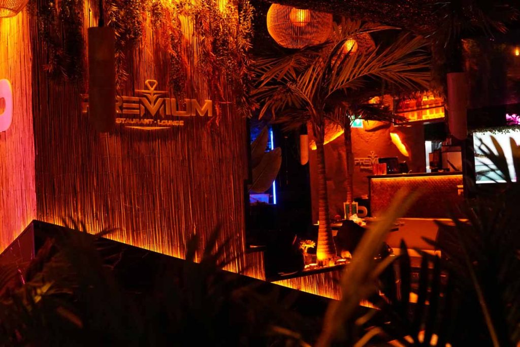 Beleuchteter Eingangsbereich mit Palmen und Lounge-Ambiente in der Shisha Bar Hamburg Hauptbahnhof.